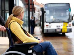 rolstoelgebruiker wacht op de aankomende bus